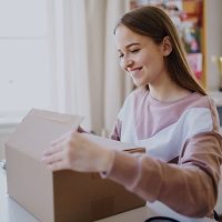 usmiechnieta dziewczyna w dlugich wlosach otwiera pudelko drugie życie Twoich ubrań