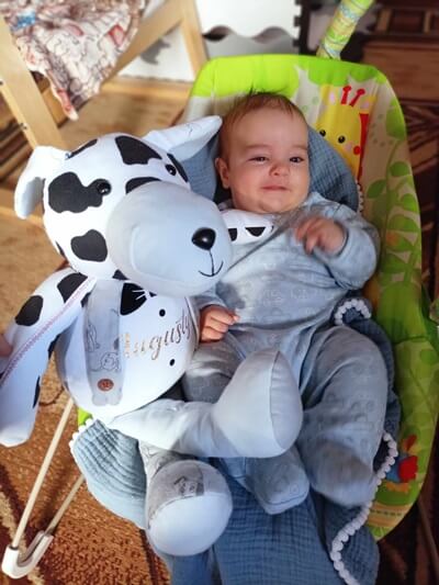 Chłopczyk leży z pluszakiem pieskiem